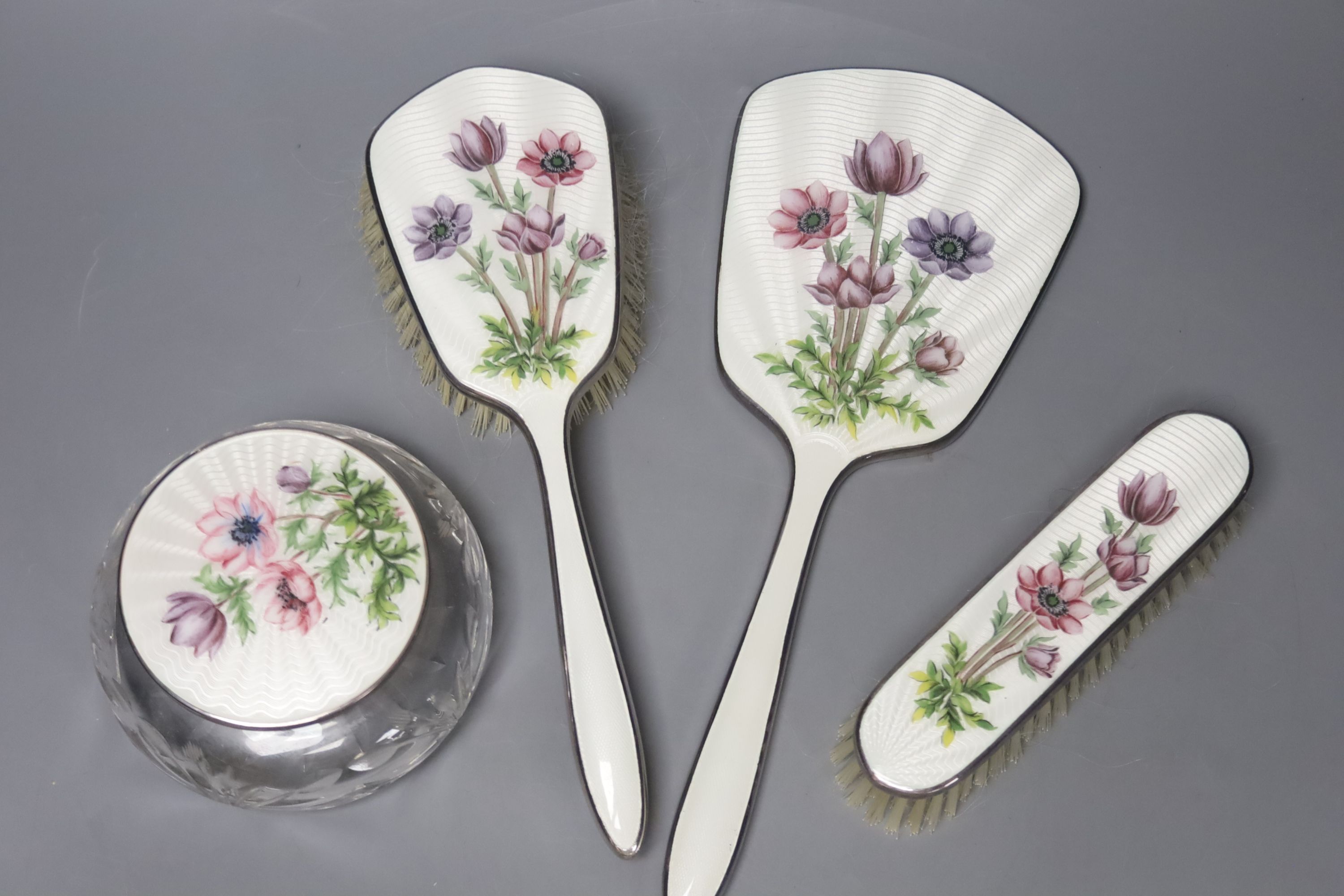 A four-piece silver plated and enamel dressing table set